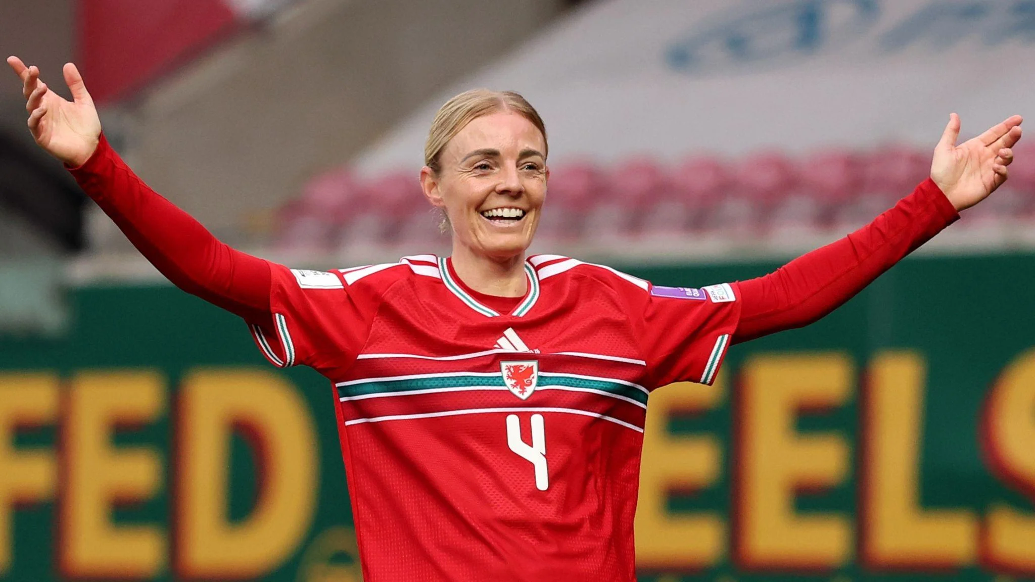 Sophie Ingle in her Wales number four jersey smiles with arms open wide